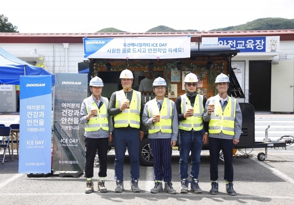 경남 합천군에 위치한 함양-창녕간 고속도로 건설현장에서 두산에너빌리티와 협력사 직원들이 커피차 앞에서 기념촬영을 하고 있다. (사진=두산에너빌리티)