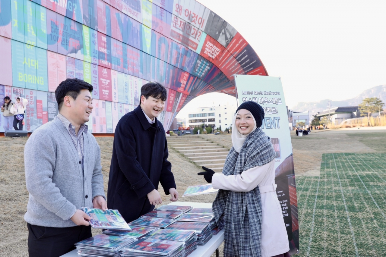 시민이 휴머나이즈 월에서 마우스패드에 인쇄된 부분을 찾아 기념사진을 찍고 있는 모습