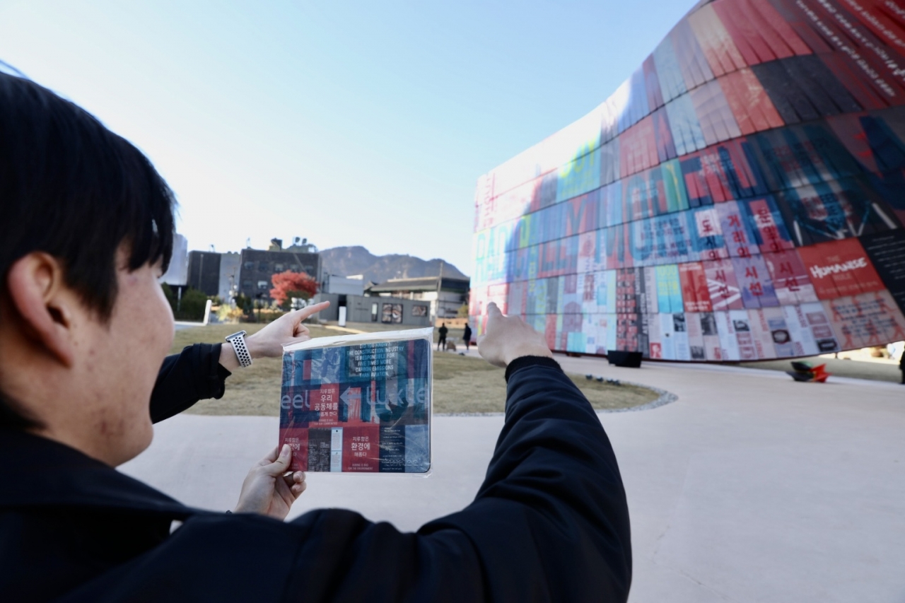 시민이 휴머나이즈 월에서 마우스패드에 인쇄된 부분을 찾아 기념사진을 찍고 있는 모습