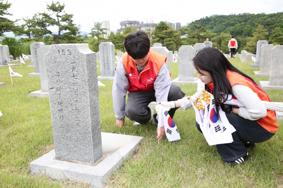 SKC 구성원들이 국립서울현충원 묘비 앞에 태극기를 꽂으며 묘역 정화 활동을 실시하고 있다./SKC 제공