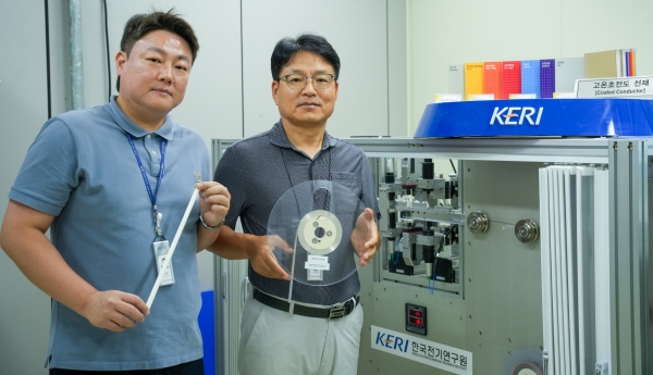 (왼쪽부터)KERI 박인성·하홍수 박사가 고온초전도 선재를 들고 3D 비접촉 초정밀 검사 장비 옆에서 포즈를 취하고 있다. (사진=전기연구원)